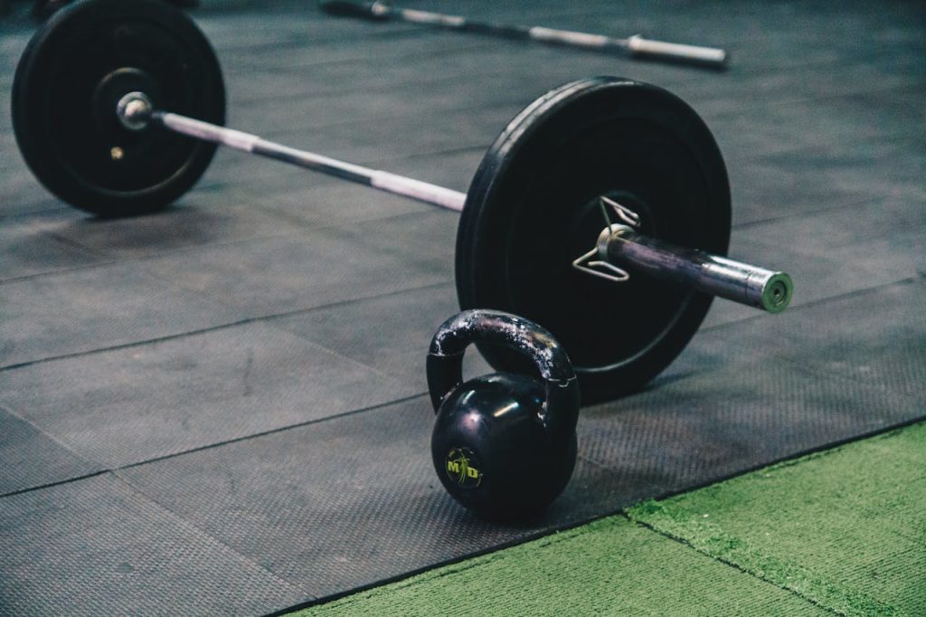 Barbell and kettlebell on gym floor, ideal for fitness and strength training themes.